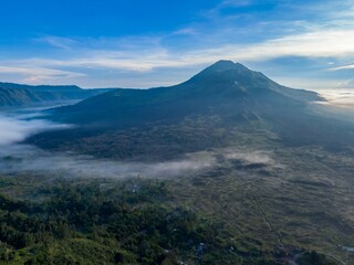 Aerial view of Mount Batur volcano in Bali, Indonesia, shrouded in morning mist. The image captures...