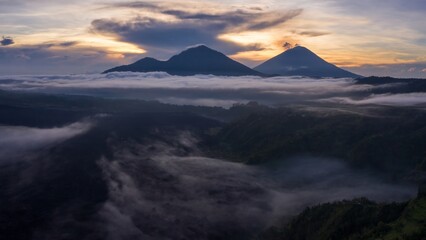 Sunrise over the Batur volcano in Bali, Indonesia. The fog covers the forest and lake below,...