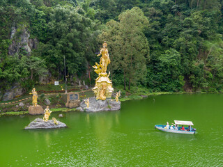 Tourists in a boat view the golden statues of Dewi Danu, the Balinese water goddess, at Danau...