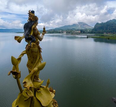A golden statue of Dewi Danu, the Balinese water goddess, stands overlooking Lake Batur in Bali, Indonesia. The statue is a symbol of prosperity and fertility.