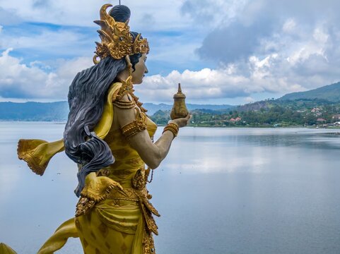A golden statue of Dewi Danu, the Balinese water goddess, stands overlooking Lake Batur in Bali, Indonesia. The statue is a symbol of prosperity and fertility.