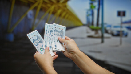 Man holding chinese yuan banknotes outdoors on a city street, symbolizing finance and business...