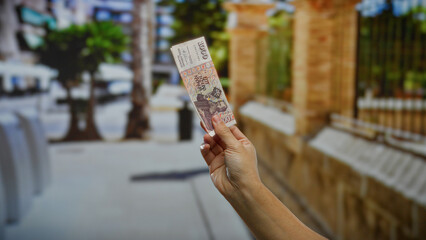 Woman holding icelandic krona in an urban street showcasing currency in an outdoor city...