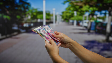 Man counting hong kong dollars on an urban street, highlighting investment and currency themes in a...