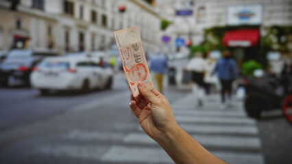 Man holding banknote with singaporean dollars in urban city street showcasing a bustling outdoor environment with cars and pedestrians in background. © Krakenimages.com