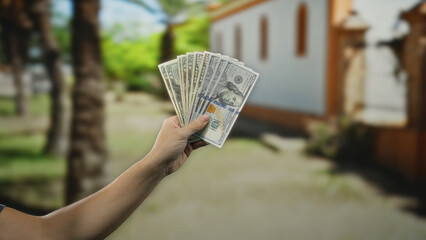 Man holding american dollars on a city street showcasing wealth in an urban outdoor setting,...