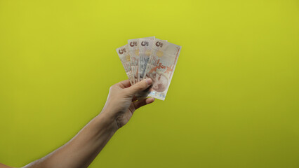 Man holding turkish lira banknotes against an isolated yellow background conveys concept of finance...