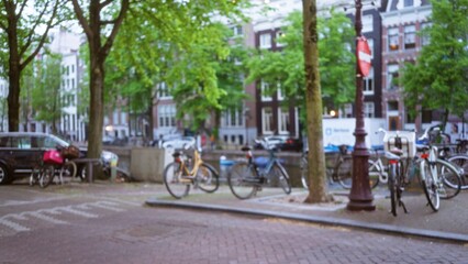 Blurry view of bicycles parked along a canal in amsterdam with trees and traditional architecture...