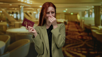 Woman with red hair holds a chinese passport, looking displeased in a restaurant, indicating a bad...