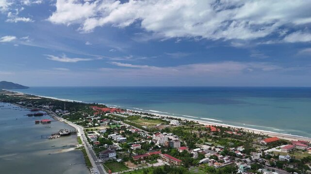 Aerial drone view of Lang Co town, Hue, Vietnam in the afternoon. Stunning coastal scenery with calm blue waters, fishing boats, sandy beaches, and lush green mountains under soft natural light. Ideal