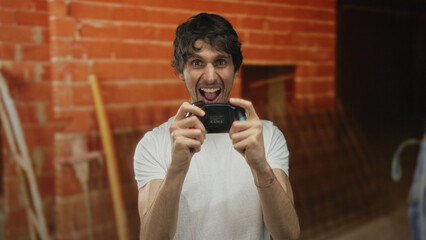 Man wearing a white t shirt holding a game controller with both hands in building under...