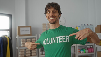 Man pointing finger to volunteer shirt in donation center building; compassion drive support...