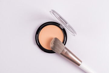 Chic round open pack of compact powder in a natural tone on a white background with a professional...