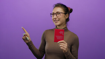 Young woman holding a swiss passport pointing to the side against a purple wall, expressing travel...