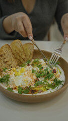 Woman enjoying delicious poached eggs and toast in a modern, luxury restaurant setting, highlighting the gourmet presentation.