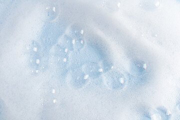 Lots of beautiful clear soap bubbles on the white surface of the detergent. white soapy texture. blue water surface. layout to advertise your product.