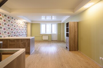 Bright room with floral wallpaper, wooden cabinets, and laminate flooring leading to a window and balcony door