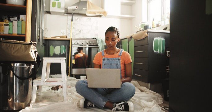 Painting, laptop and woman in home for renovation, interior design or online shopping for supplies. Computer, remodeling kitchen and African person on floor for house improvement with creative ideas - Powered by Adobe