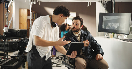 Man, director and producer with tablet for scene, playback or discussion in production studio. Male...