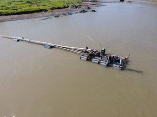 Aerial photo of river sand mining with floating ship and long pipe machinery 
