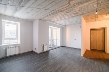 An empty room under renovation with grey flooring, white walls, and a concrete ceiling with visible...