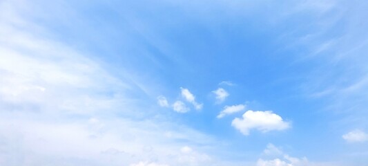 Beautiful scene of soft fluffy white clouds floating in a clear blue sky on a bright summer day,...