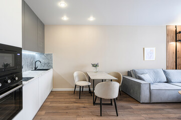 Modern apartment interior. Features kitchen area with sleek appliances, a dining table set, and a...