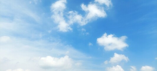 A stunning background of a clear blue sky with delicate white cloud formations on a bright sunny day. Peaceful and serene atmosphere, suitable for themes related to nature, weather, relaxation, travel