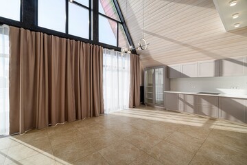 Bright interior featuring tile flooring, a peaked ceiling, kitchen cabinets, and large windows...