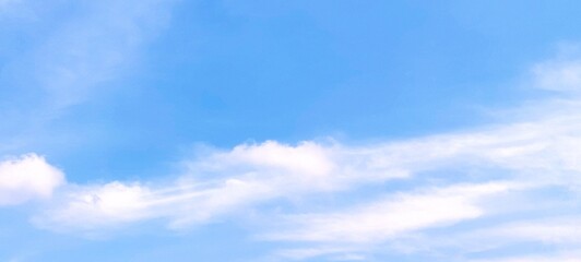 Beautiful scene of soft fluffy white clouds floating in a clear blue sky on a bright summer day, creating a calm and serene atmosphere. Ideal for nature, travel, relaxation, weather themed designs.