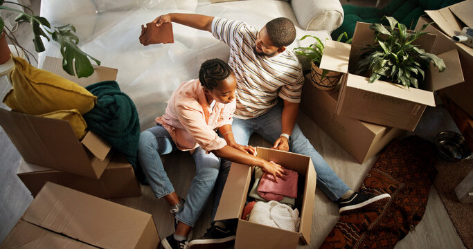 Unpacking, couple and people with boxes, moving in and bonding in new house, mortgage or investment. Relocation, black man and woman with cardboard in living room, real estate and unboxing in home