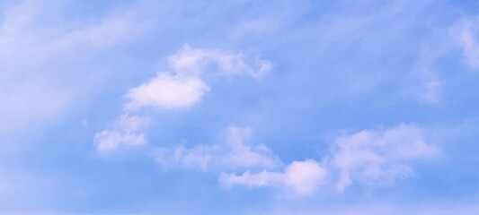 A stunning background of a clear blue sky with delicate white cloud formations on a bright sunny day. Peaceful and serene atmosphere, suitable for themes related to nature, weather, relaxation, travel