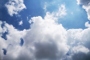 Dramatic sky with bright sun rays bursting through thick cumulus clouds, creating a powerful and...