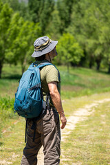 Mature hiker pausing, taking in panoramic mountain vista during wilderness trek with loaded backpack