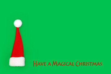Magical Christmas concept with red santa hat decoration on green background. Xmas Eve symbol for...