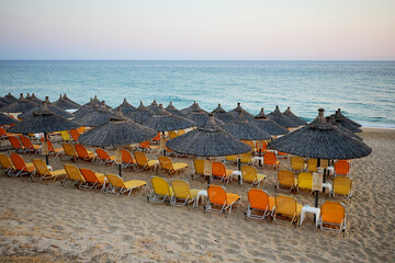 beach by the sea with yellow and orange loungers and umbrellas