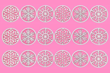 White snowflake wooden Christmas tree decorations background pattern on pink. Natural wooden traditional symbols for decorative gift tag, greeting card, label. 