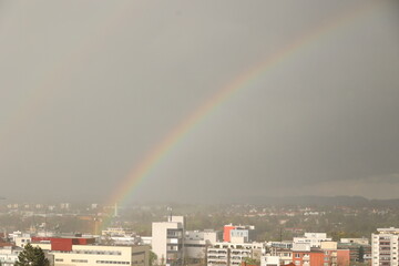 A rainbow is seen in the sky above a city