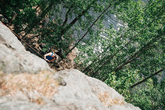 man climbing a rock outside by a lake in Sweden