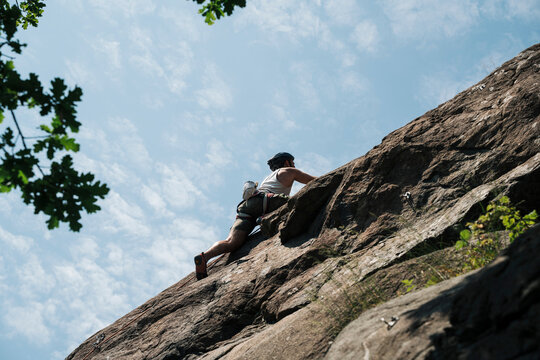 man climbing a huge rock whilst in the Swedish archipelago