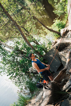 man wearing climbing glasses whilst belaying next to the sea