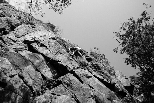 man climbing a huge rock whilst outdoor climbing