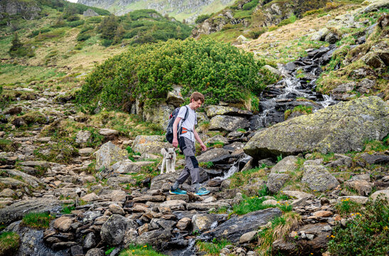 Man hiking with dog along rocky stream in Austrian Alps