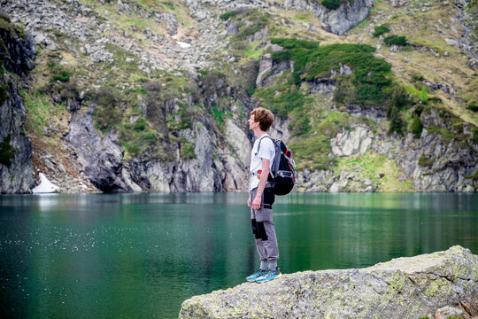 Man standing on rock by alpine lake in the Austrian mountains