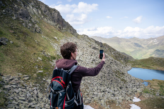 Man takes photo of mountain landscape with smartphone in Austrian Alps
