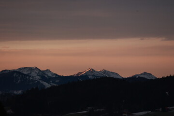 The mountains are covered in snow and the sky is a beautiful pink color