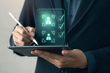 Person using stylus on tablet displaying glowing human icons with checkmarks
