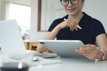 Asian business woman using digital tablet and laptop computer for online meeting during remote...
