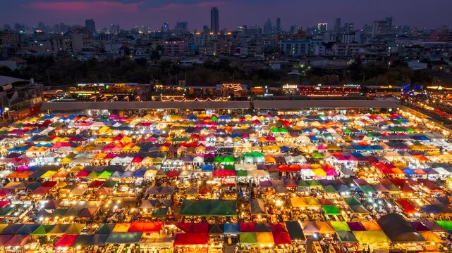 [Zoom Out] Time lapse video from dusk to night view of the Train Night Market Ratchada, Bangkok, Thailand