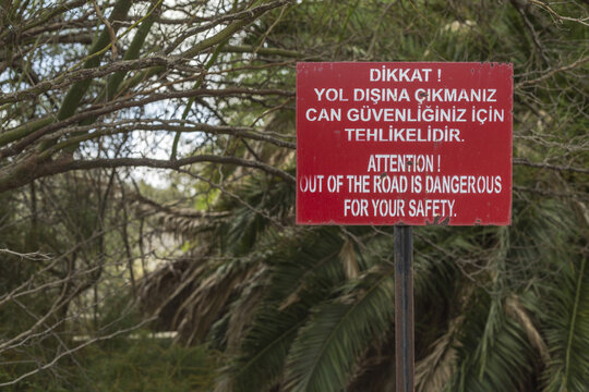 Varosha, Cyprus - 25 June 2025: View of a stark red and white warning sign against a backdrop of muted greens and browns, a silent sentinel in a forgotten place.